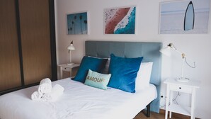 A neatly made bed with white linens and a pillow with the word "AMOUR".