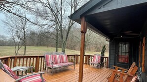 A wooden deck with outdoor seating and a view of a wooded area.