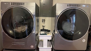 Two stacked front-loading Whirlpool washers with a control panel, a small white appliance in between, and a tiled floor.