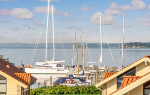 A marina with multiple sailboats docked, surrounded by residential buildings with sloped roofs.