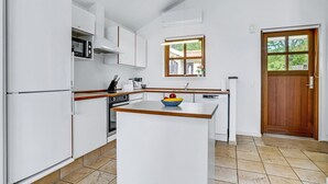 Eine moderne Küche mit weißen Schränken, einer zentralen Kochinsel und einer Holztür.