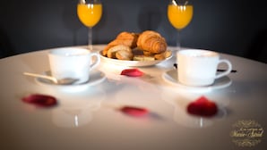 Un desayuno con cruasanes, zumo de naranja y café sobre una mesa.
