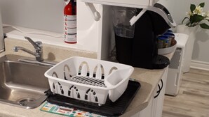 Una cucina con lavello, un armadietto bianco, un piano di lavoro bianco e una stufa nera.