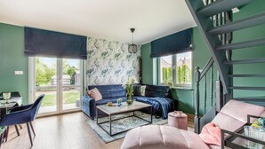 Un salon moderne avec un canapé bleu, un canapé rose, une table basse et un escalier.