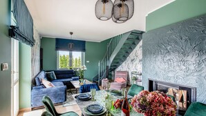 Un salon moderne avec un canapé bleu, une table à manger dressée avec des assiettes et des verres, et un escalier menant à un niveau supérieur.