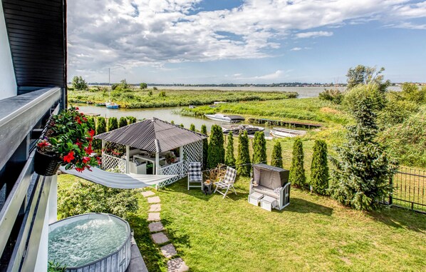 Un jardín con jacuzzi, zona de estar y vista a un río con barcos.