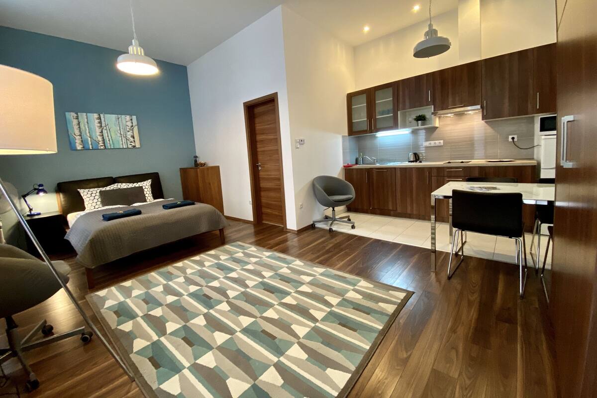 Un apartamento moderno con un dormitorio, una pequeña cocina y un comedor.
