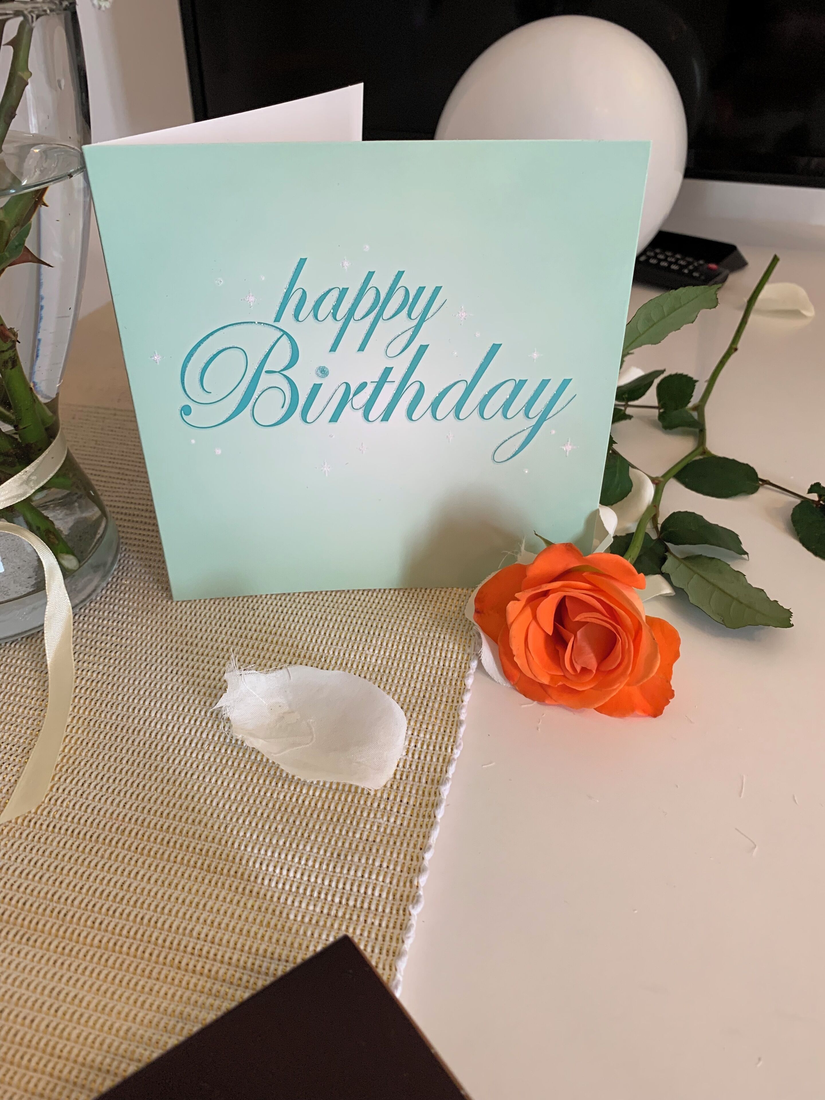 Een verjaardagskaart met de tekst 'happy Birthday', geplaatst op een tafel met een geweven placemat.
