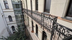 Um edifício com várias andares, varandas, janelas amplas e grade de ferro forjado.