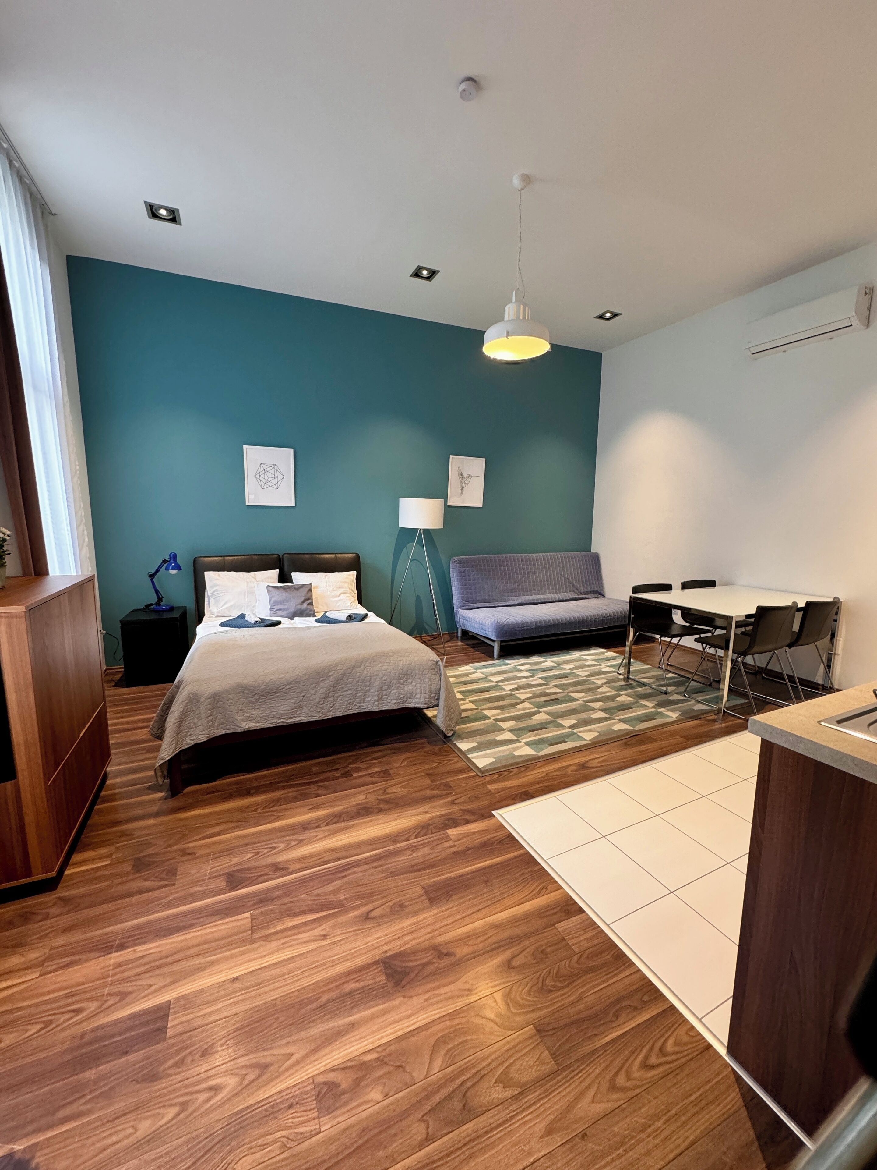A bedroom with a bed, a desk, a chair, a lamp, and a rug.