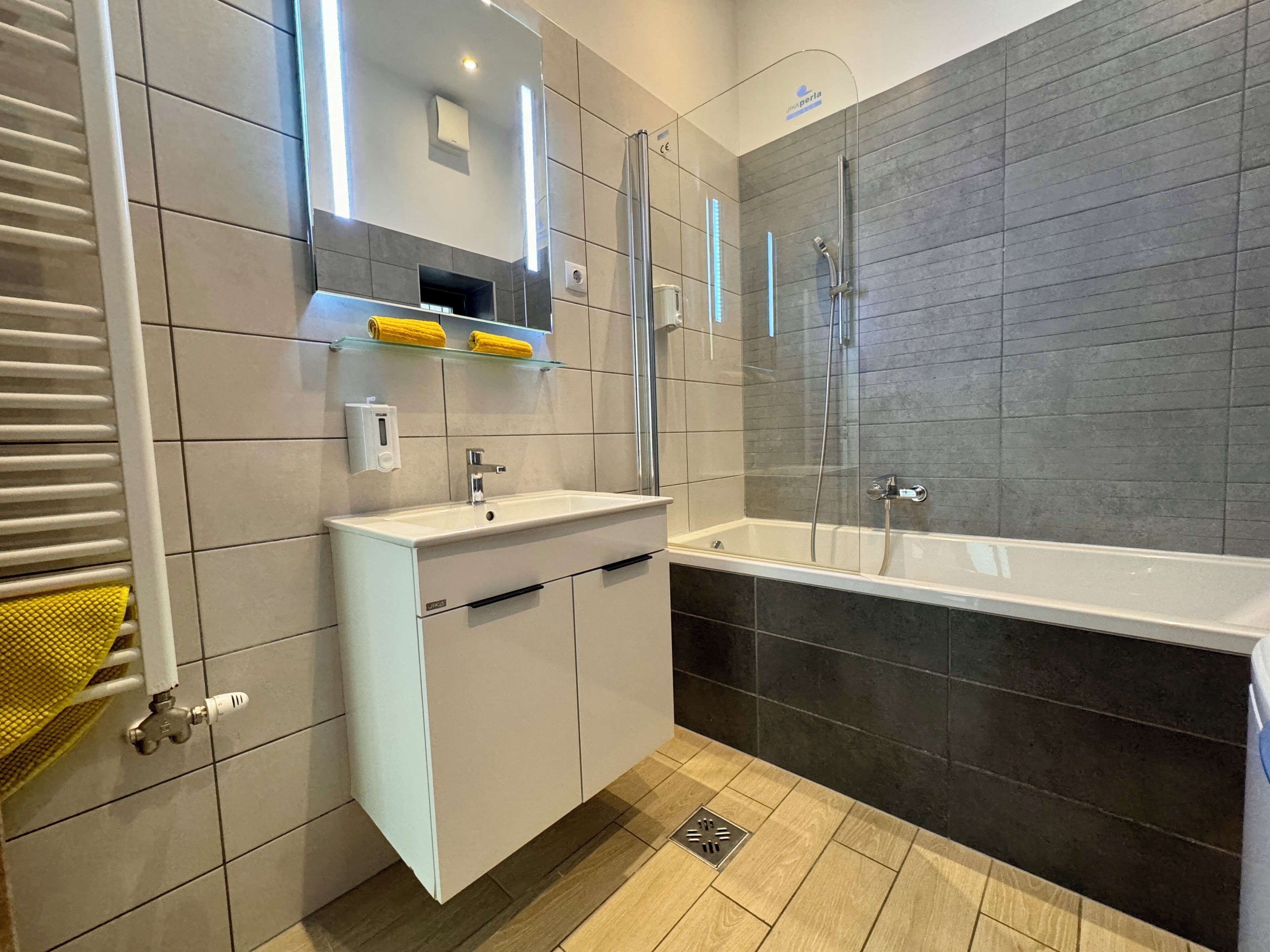 Un baño moderno con tocador blanco, cabina de ducha de cristal y bañera.