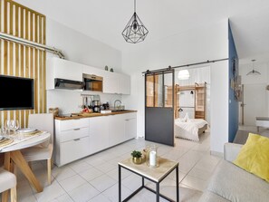 A modern kitchen with a flat-screen TV, wooden countertop, and a sliding door leading to a bedroom.