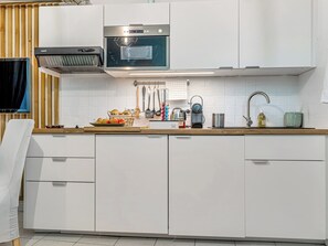 A modern kitchen with white cabinets, a stainless steel oven, and various kitchen utensils.