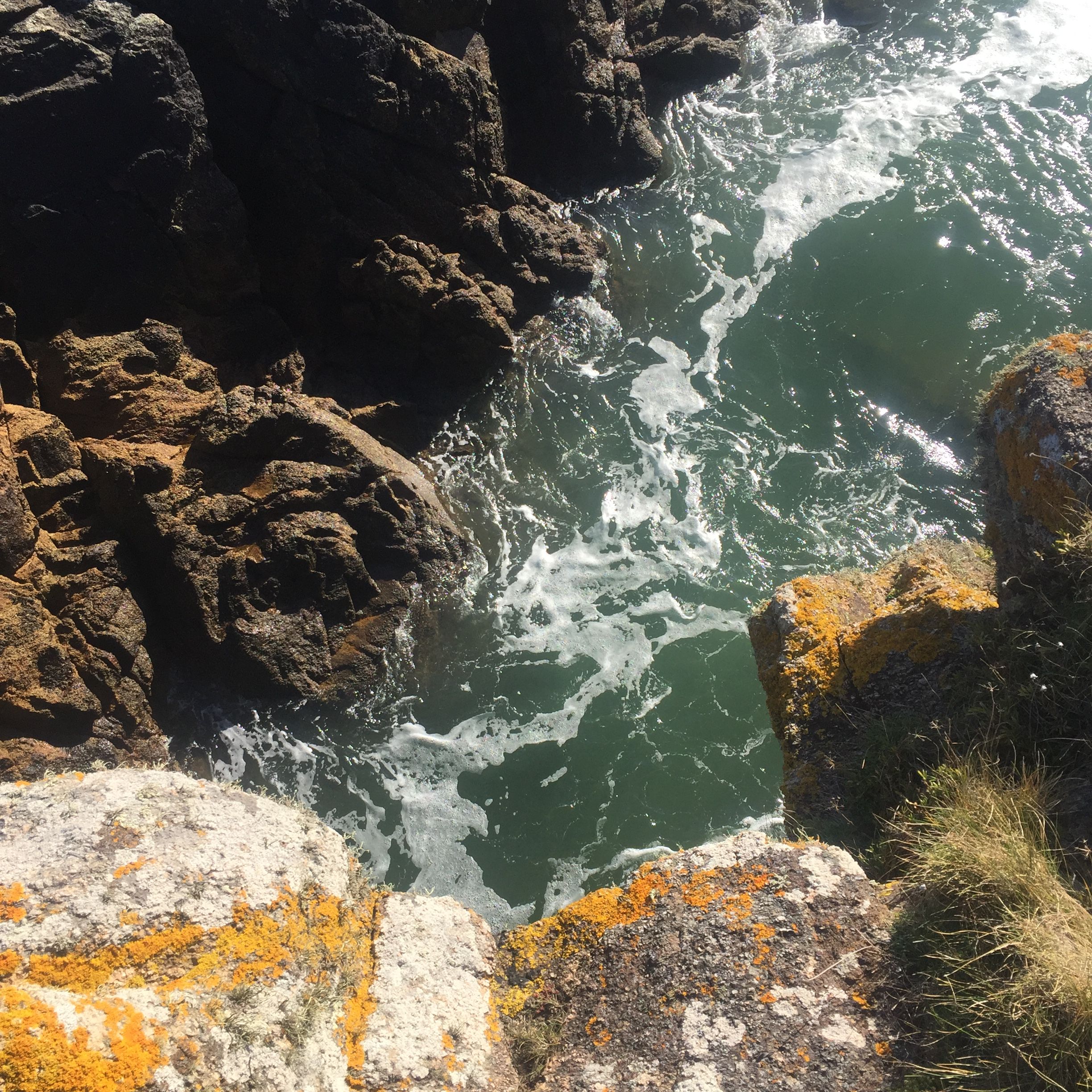 Une côte rocheuse où les vagues s'écrasent contre les rochers.