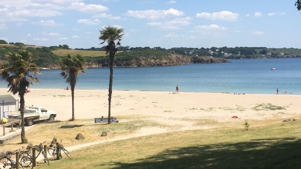A beach with a clear view of the sea, a few people, and some trees. - Welcome to Rue des oiseaux (Névez)