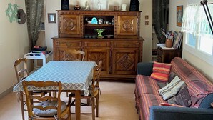 A cozy living room with a dining table, wooden cabinets, and a sofa. - Welcome to Rue des oiseaux (Névez)