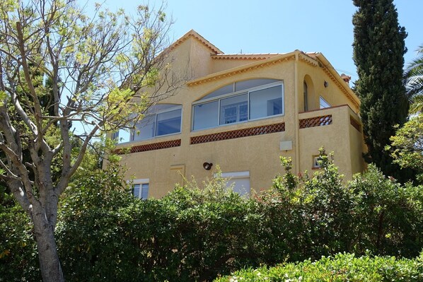 A two-story building with a yellow facade, large windows, and a decorative balcony.