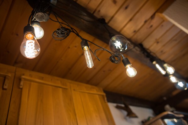 Techo con vigas de madera a la vista y lámparas Edison colgantes.