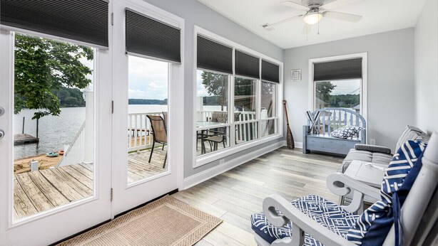 A spacious deck with large windows overlooking a lake, furnished with chairs and a table. - Lakefront, two bedroom, full bath. Relax, swim, kayak & fish on Lake Lookout. (Claremont)