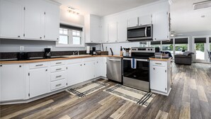 A modern kitchen with white cabinets, a microwave, an oven, and a dishwasher. - Lakefront, two bedroom, full bath. Relax, swim, kayak & fish on Lake Lookout. (Claremont)
