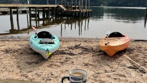 Two kayaks on a sandy beach with a wooden dock in the background and a clear sky. - Lakefront, two bedroom, full bath. Relax, swim, kayak & fish on Lake Lookout. (Claremont)