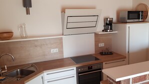 Cocina compacta con lavamanos, estufa, microondas y cafetera.