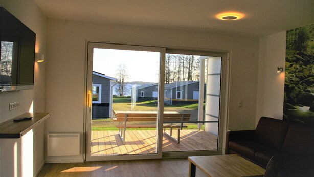 Un salon moderne doté d’une porte-fenêtre coulissante donnant sur une terrasse extérieure.