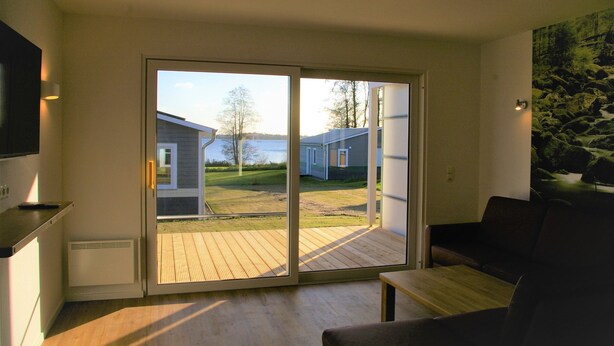 A modern living room with a large sliding glass door leading to an outdoor deck.