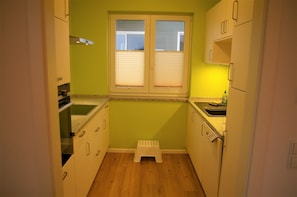Une cuisine compacte avec une fenêtre, un petit tabouret et un plan de travail.