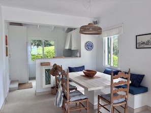 A dining area with a wooden table, chairs, and a hanging light fixture.