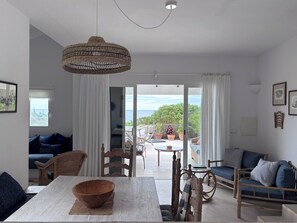 A modern living room with a dining table, sofas, and a view to an outdoor patio.