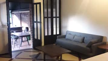 A room with a bed, a sofa, a coffee table, and a dining area with chairs and a table.