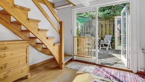 A wooden staircase leading to a room with a sliding glass door, a wooden dresser, and a patterned rug. - Cozy home in Stubbekøbing with kitchen (Stubbekøbing)