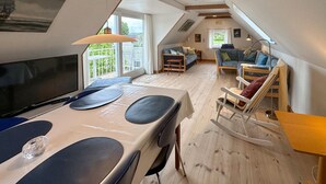A cozy attic room with a dining table, a TV, and a rocking chair. - Cozy home in Stubbekøbing with kitchen (Stubbekøbing)