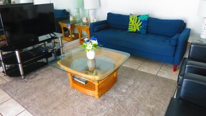 Un salon comprenant un téléviseur, un canapé, une table basse et des coussins décoratifs.