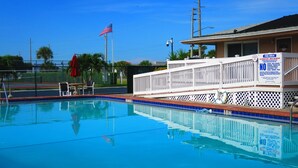 Une piscine d’un bleu éclatant, entourée d’une clôture blanche et dotée d’un poste de surveillance pour les sauveteurs.