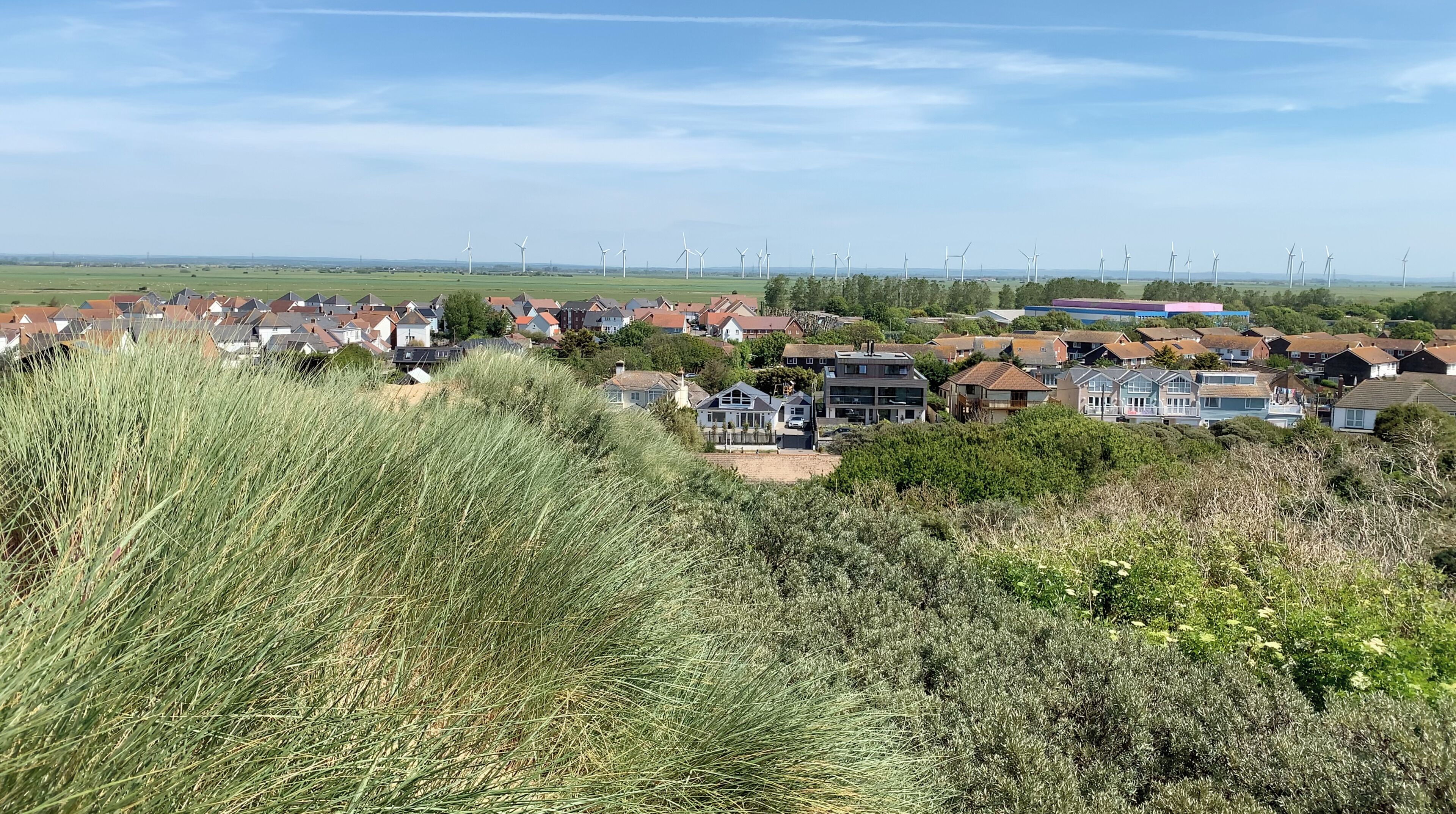 Un quartier résidentiel avec des maisons, des éoliennes et un ciel dégagé.