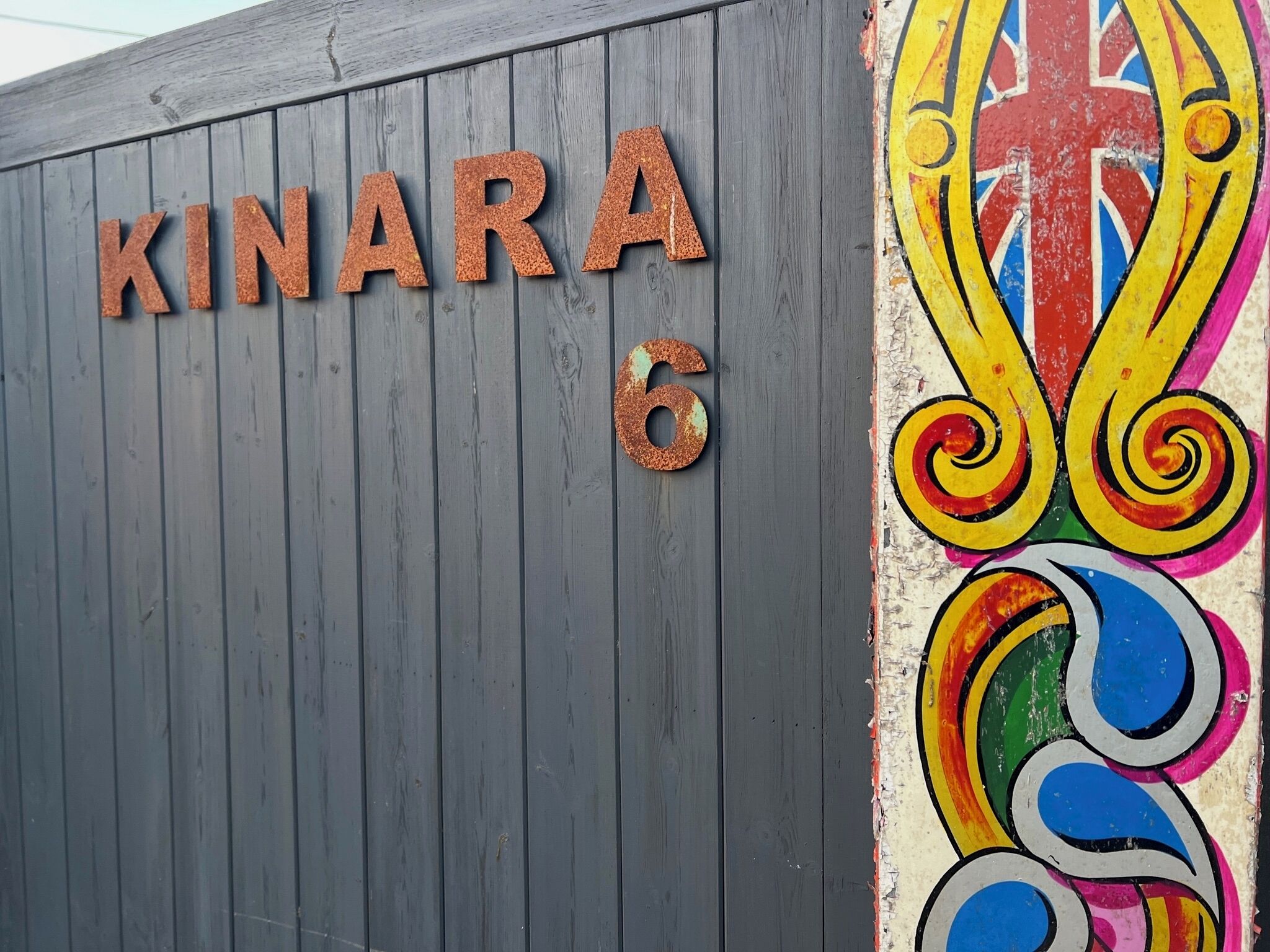 En bygning med en træfacade og et farverigt muralmaleri.