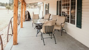 A covered porch with wooden beams, a concrete floor, and a table with chairs. - Tranquil Trailside (Custer)