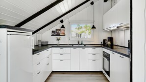 Une cuisine moderne avec des meubles blancs, un plan de travail noir et une fenêtre donnant sur la verdure.