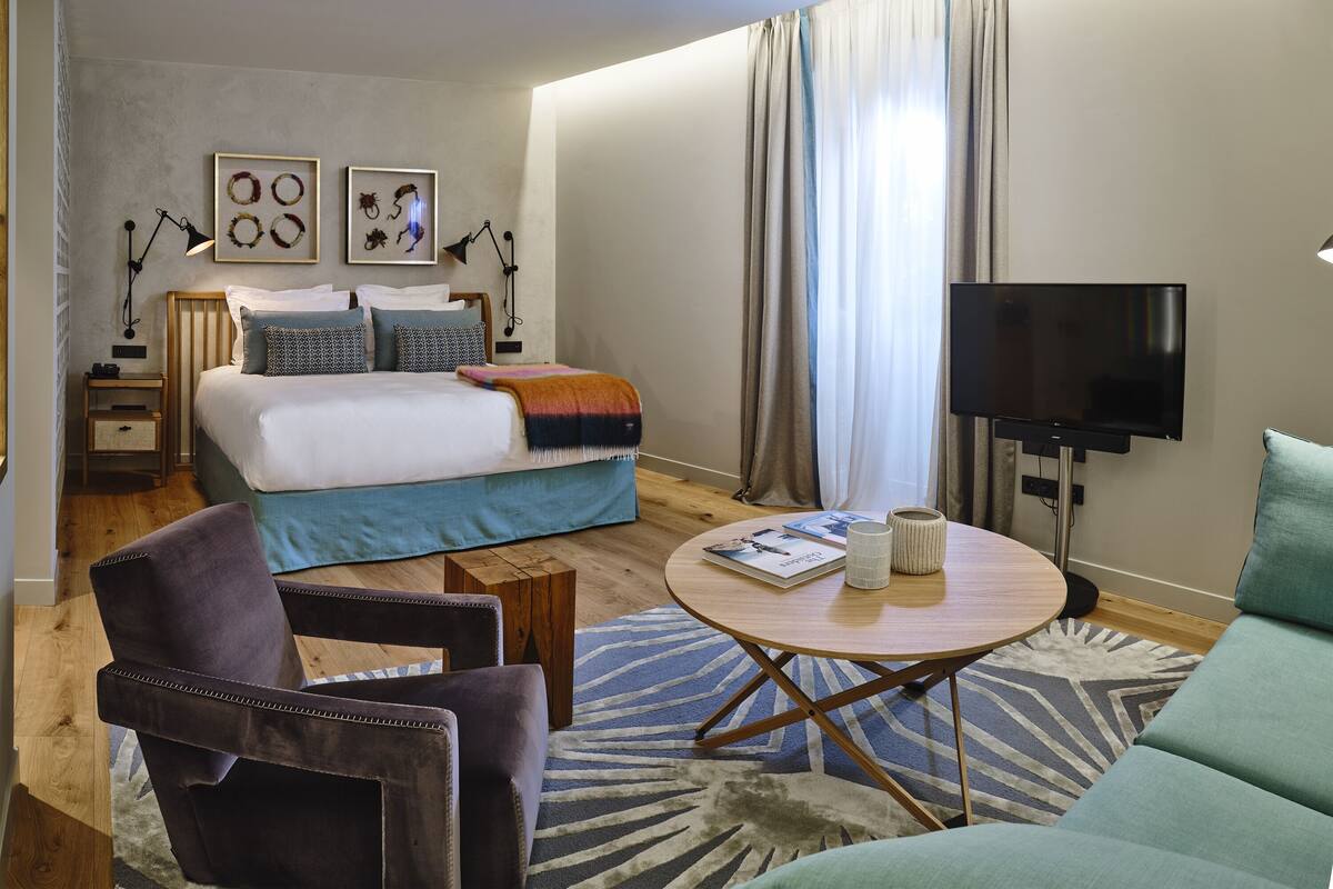 Une chambre d’hôtel moderne équipée d’un lit, d’une télévision, d’une table basse et d’un canapé.