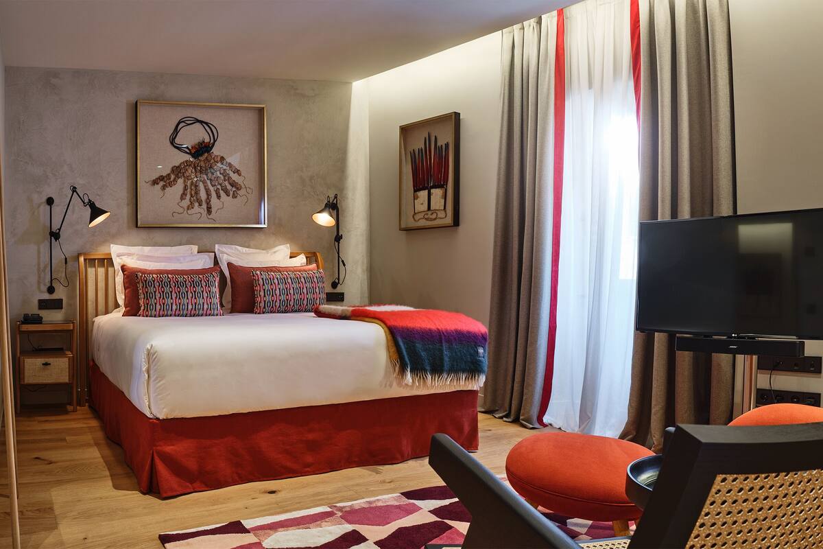 Une chambre d’hôtel avec un lit, une télévision, une chaise et un bureau.