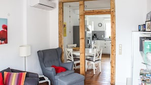 En moderne stue med en grå lænestol, et lille bord med en lampe og en bogreol med bøger.