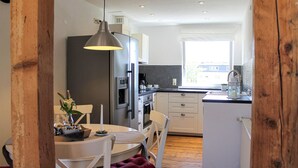 Et moderne køkken med hvide skabe, en sort bordplade og et træspisebord med stole.