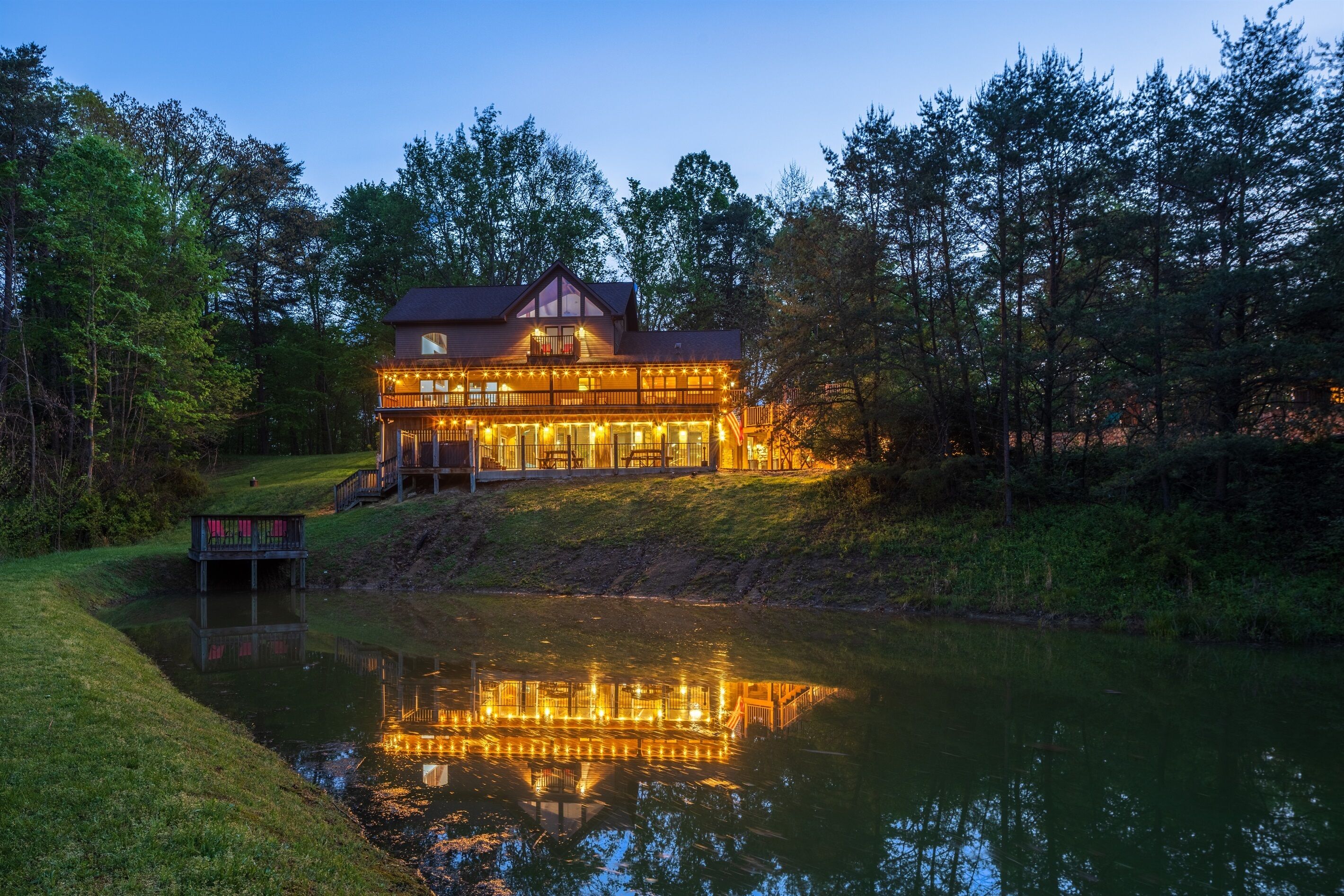 A large, multi-story lodge with a reflective pool in front, surrounded by trees.