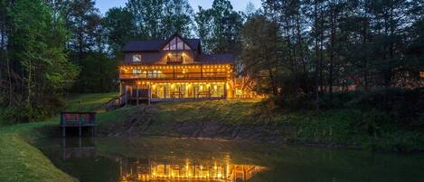 A large, multi-story lodge with a reflective pool in front, surrounded by trees.