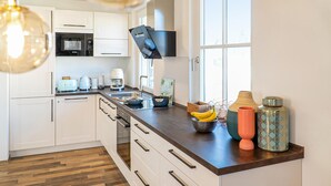 Een moderne keuken met witte kasten, een houten aanrecht en een groot raam.
