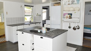 Cocina moderna con armarios blancos, encimera de granito y horno empotrado. Una ventana proporciona luz natural y vistas al exterior.