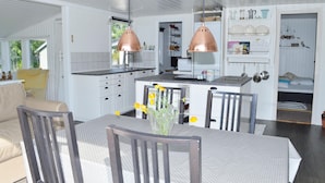 Una cocina moderna con armarios blancos, un comedor con mesa y sillas, y una pequeña kitchenette.