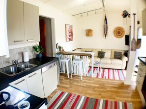 Enjoy a compact kitchen with a dining area and cozy living space featuring a sofa and a large window.